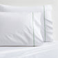 Set of 2 white percale pillowcases with a green diamond embroidered border.