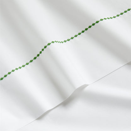 White percale sheet with a green diamond embroidered border.