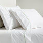 White percale sheet set with green diamond embroidery on pillowcases and flat sheet.