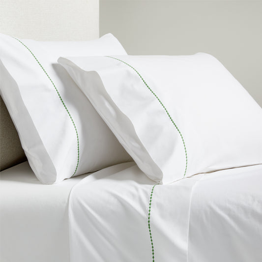 White percale sheet set with green diamond embroidery on pillowcases and flat sheet.