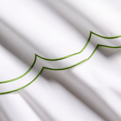 White organic cotton percale sheet with green double scallop stitch embroidery.