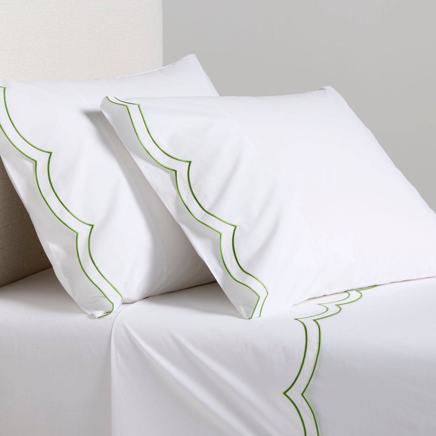 White organic cotton percale sheet set with green double scallop stitch embroidery on pillows and top sheet.