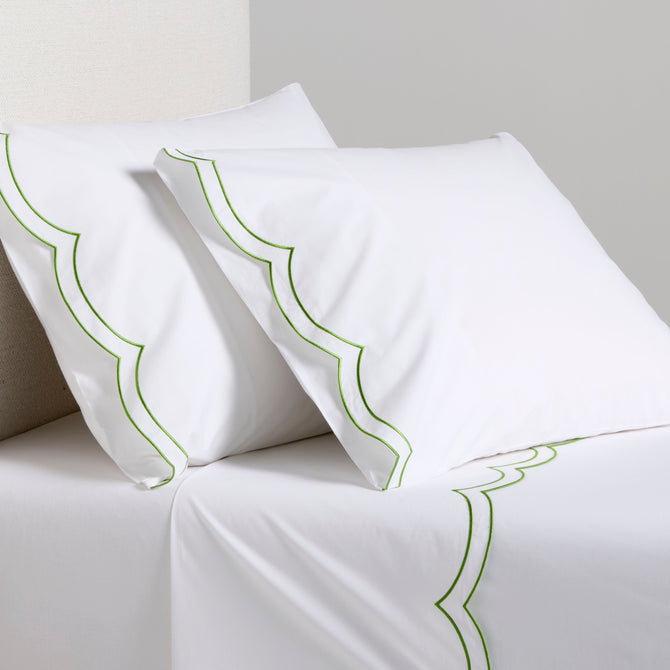 White organic cotton percale sheet set with green double scallop stitch embroidery on pillows and top sheet.