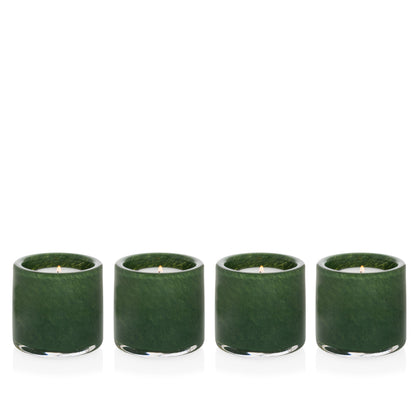 Four mouth-blown, hand-formed green votive glass candle holders with lit candles.