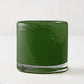 Mouth-blown, hand-formed green votive glass candle holder with clear base.