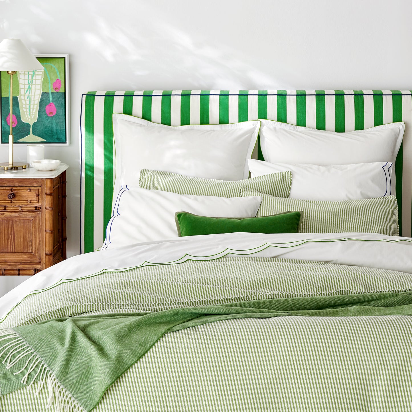 Green Italian Herringbone Throw Blanket, cashmere-soft with decorative fringe, draped over a bed.