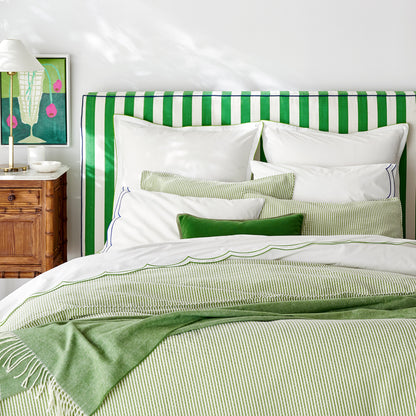 Green Italian Herringbone Throw Blanket, cashmere-soft with decorative fringe, draped over a bed.