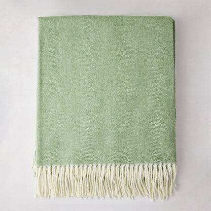Green Italian herringbone throw blanket, folded, with cream fringe.