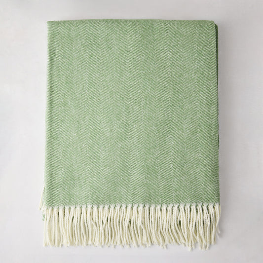 Green Italian herringbone throw blanket, folded, with cream fringe.