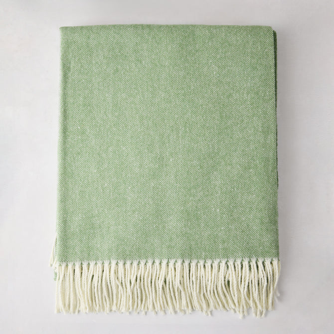 Green Italian herringbone throw blanket, folded, with cream fringe.