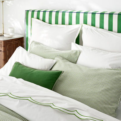 Green Linen and Velvet Reversible Lumbar Pillow, 20"L x 14"H, on a bed with white bedding.