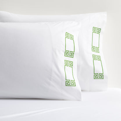 White percale pillow shams with green embroidered Greek key border.