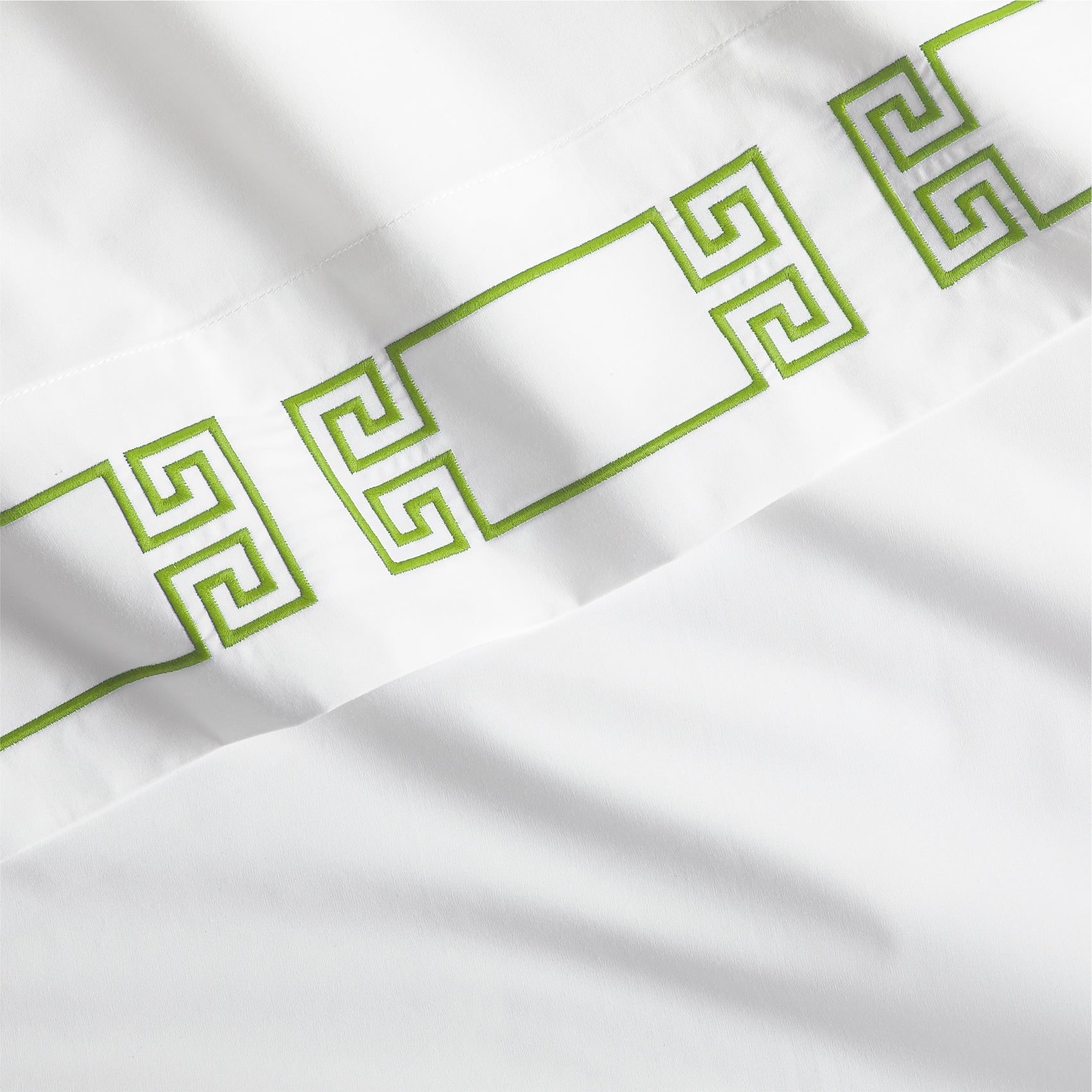 White percale sheet with a bold green embroidered Greek key band.