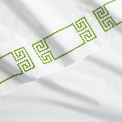 White percale sheet with a bold green embroidered Greek key band.