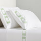 White percale sheet set with green embroidered Greek key motif on pillows and flat sheet.