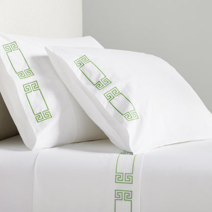White percale sheet set with green embroidered Greek key motif on pillows and flat sheet.