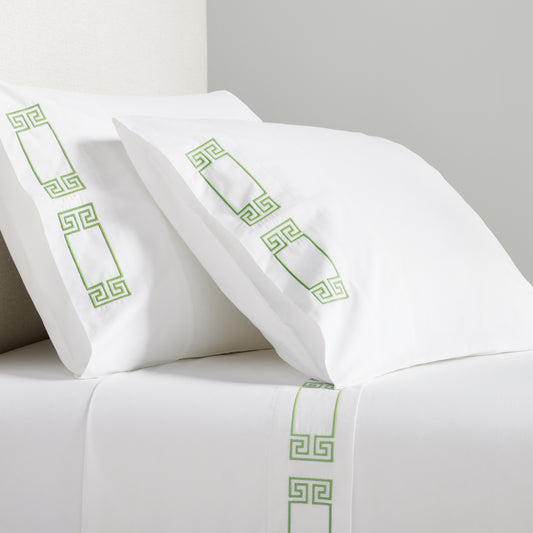White percale sheet set with green embroidered Greek key motif on pillows and flat sheet.