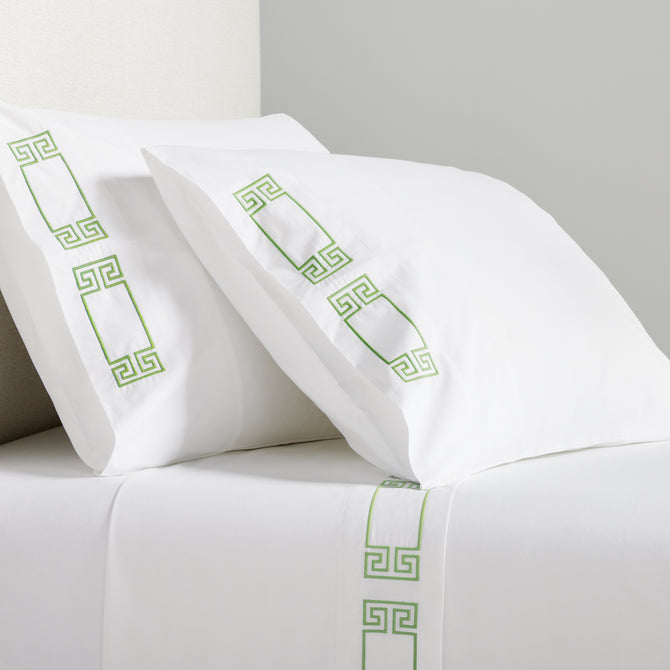 White percale sheet set with green embroidered Greek key motif on pillows and flat sheet.