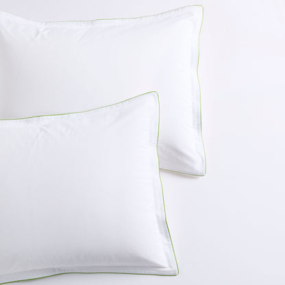 White percale duvet shams with delicate green piping and subtle double-stitch detailing.