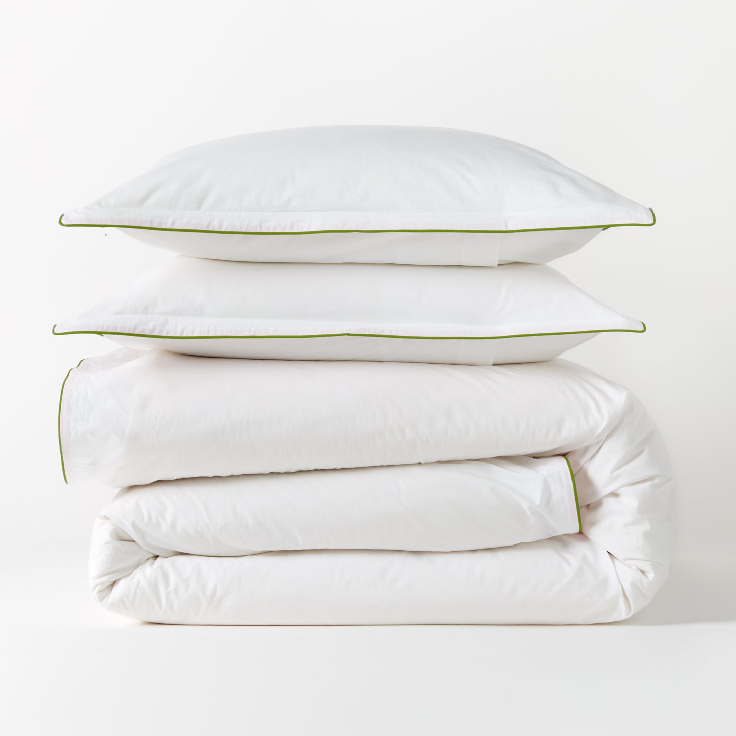 White percale duvet and two shams with green piping, stacked neatly.