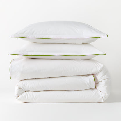 White percale duvet and two shams with green piping, stacked neatly.