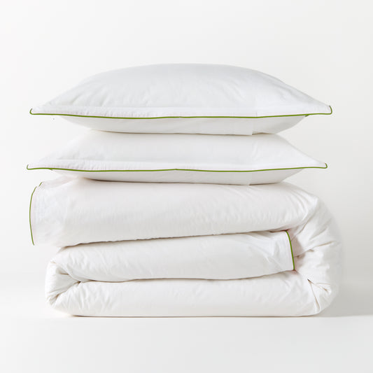 White percale duvet and two shams with green piping, stacked neatly.
