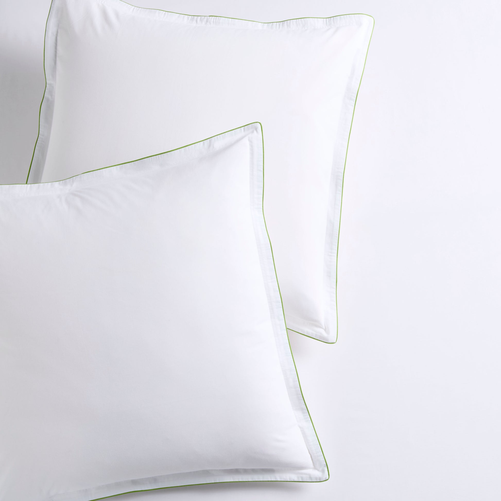 Set of two white percale Euro shams with delicate green piping and double-stitch detailing.