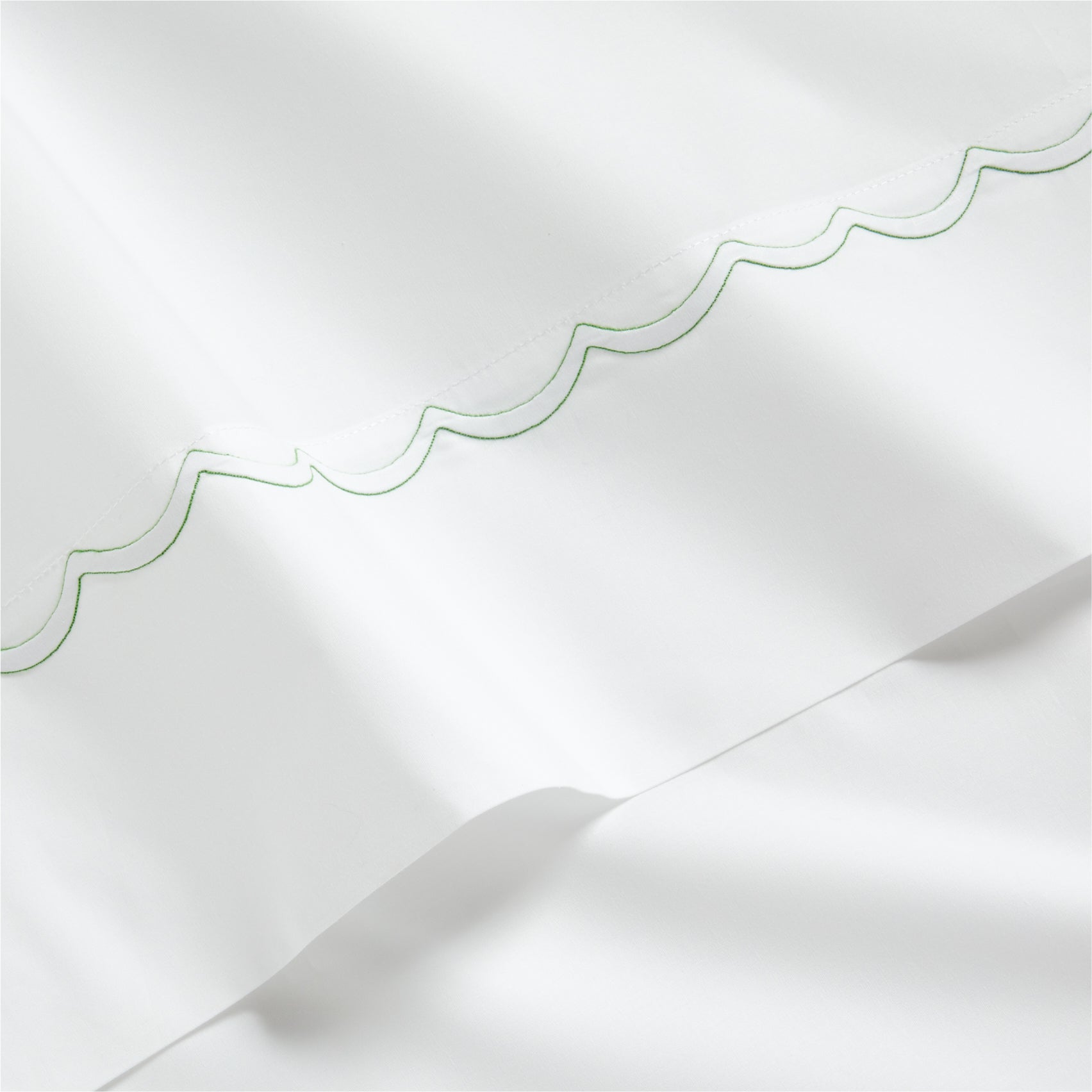 White percale sheet with green scallop stitch embroidery.