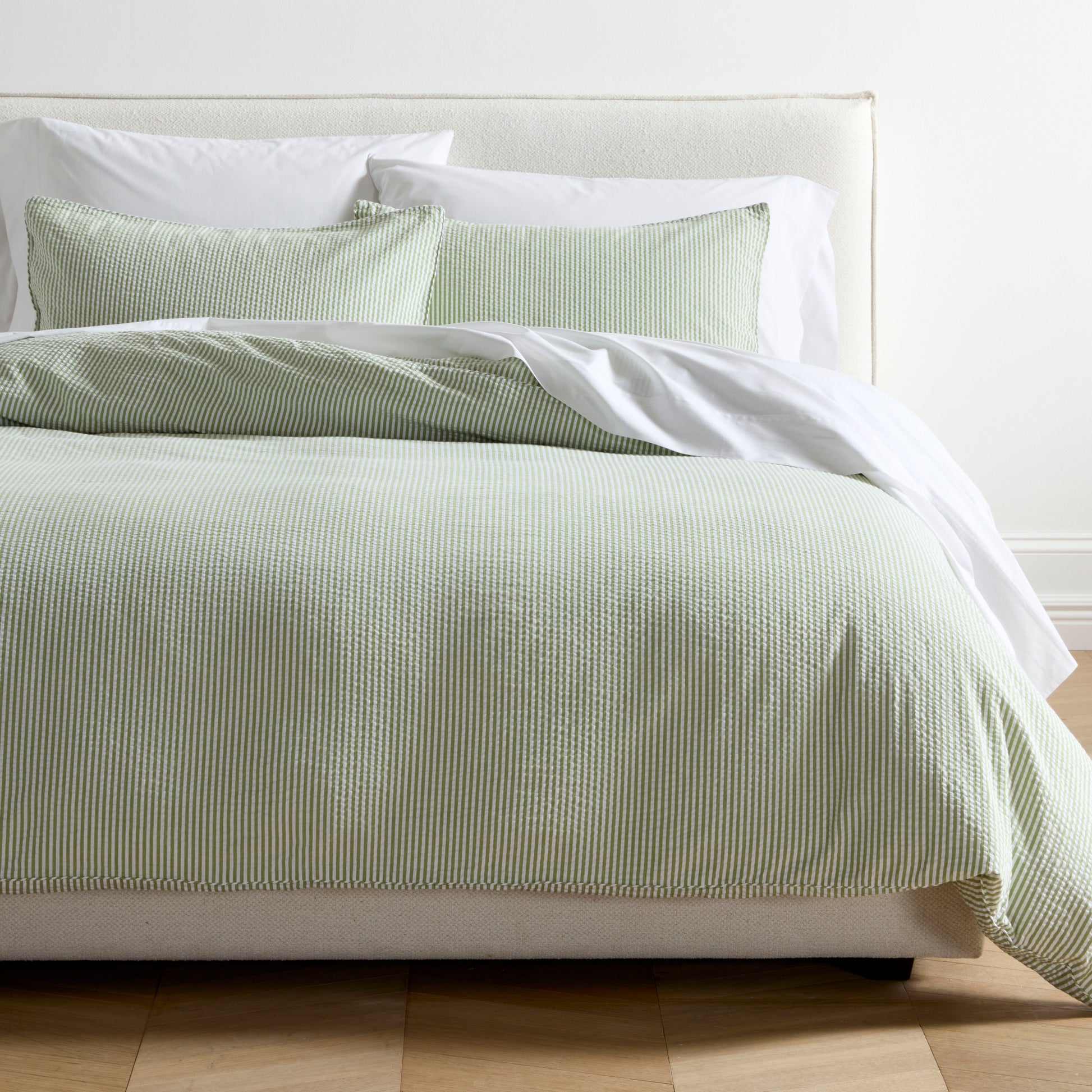 Green seersucker stripe organic cotton duvet and sham set on a bed with white sheets.