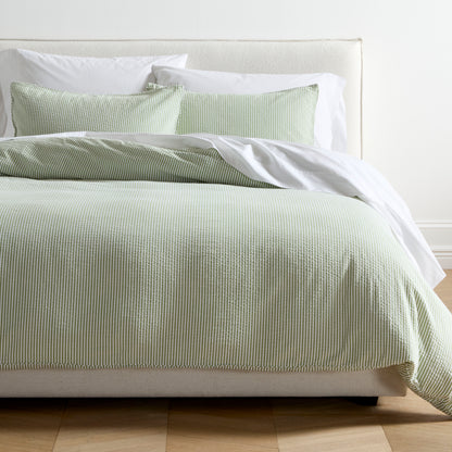 Green seersucker stripe organic cotton duvet and sham set on a bed with white sheets.