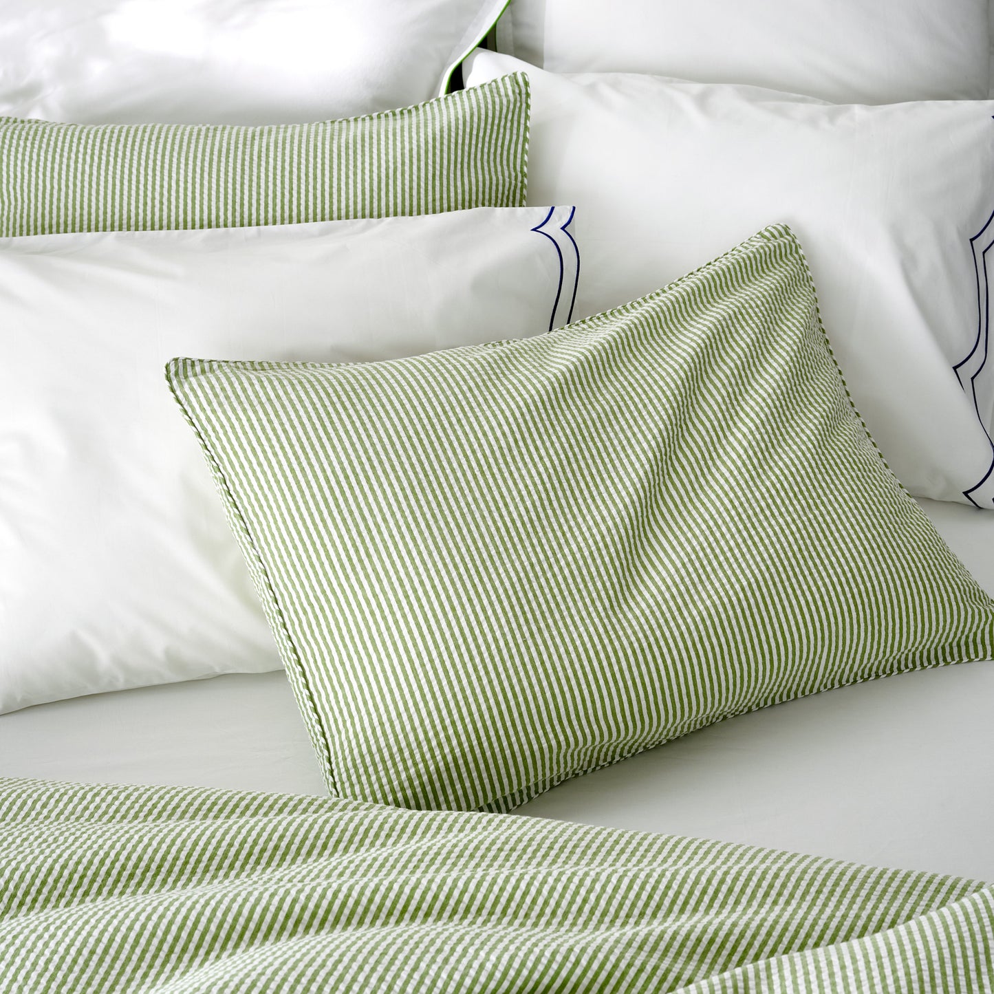 Green seersucker stripe organic cotton duvet and sham set on a white bed.