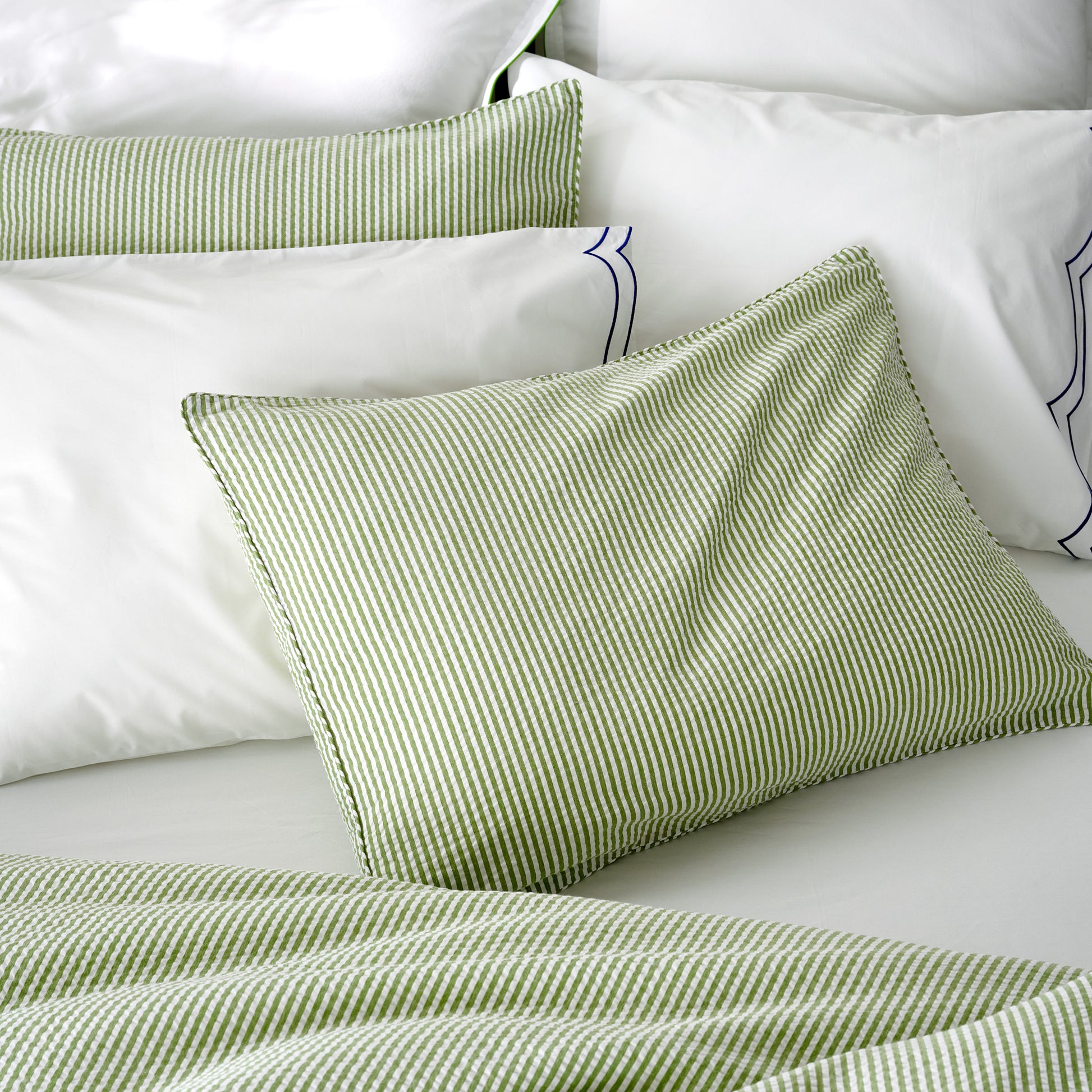 Green seersucker stripe organic cotton duvet and sham set on a white bed.