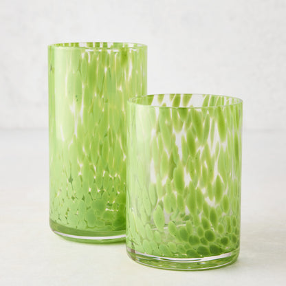 Two clear glass highball glasses with bright green spotted patterns, one tall and one shorter.