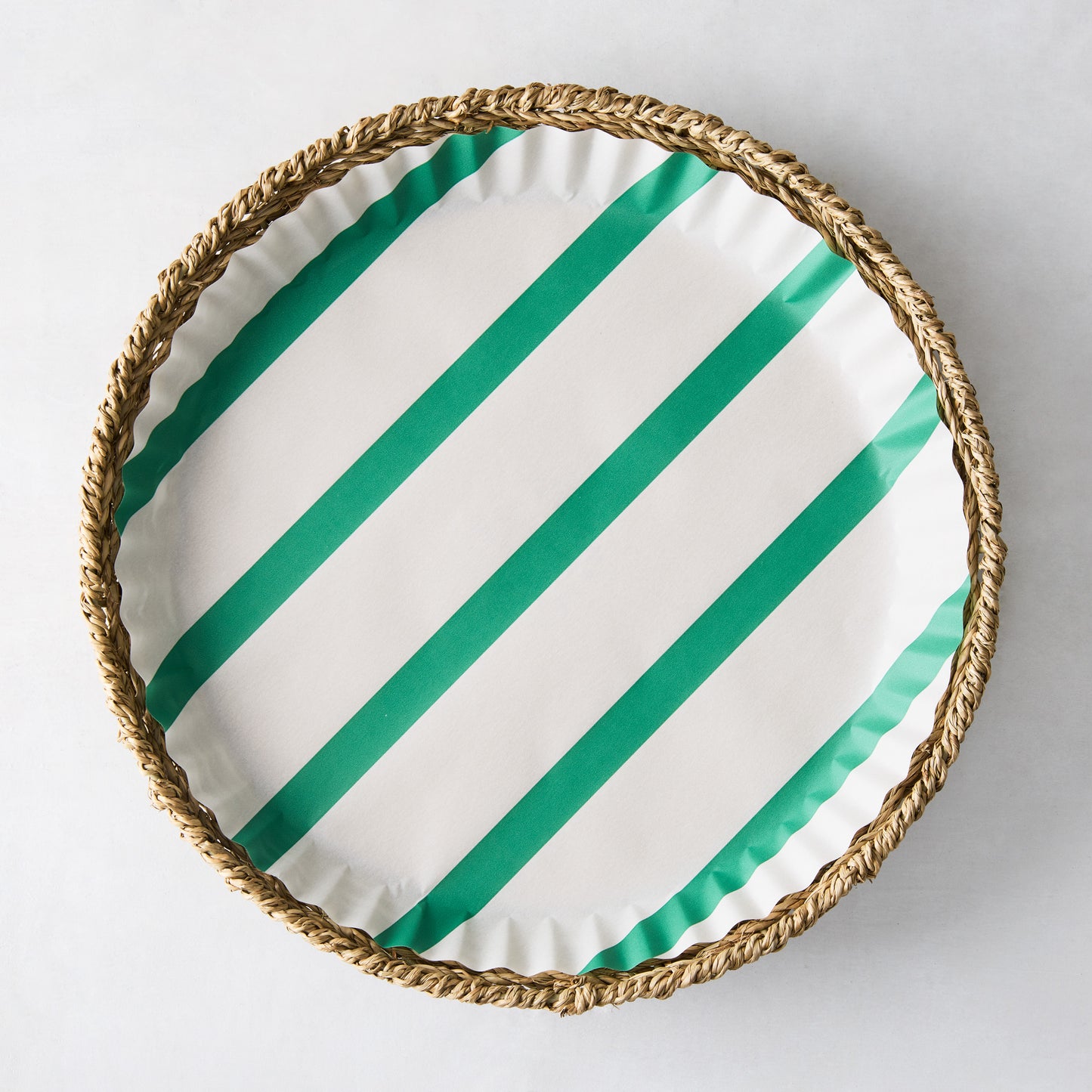 Round white parchment liner with green diagonal stripes in a woven basket.