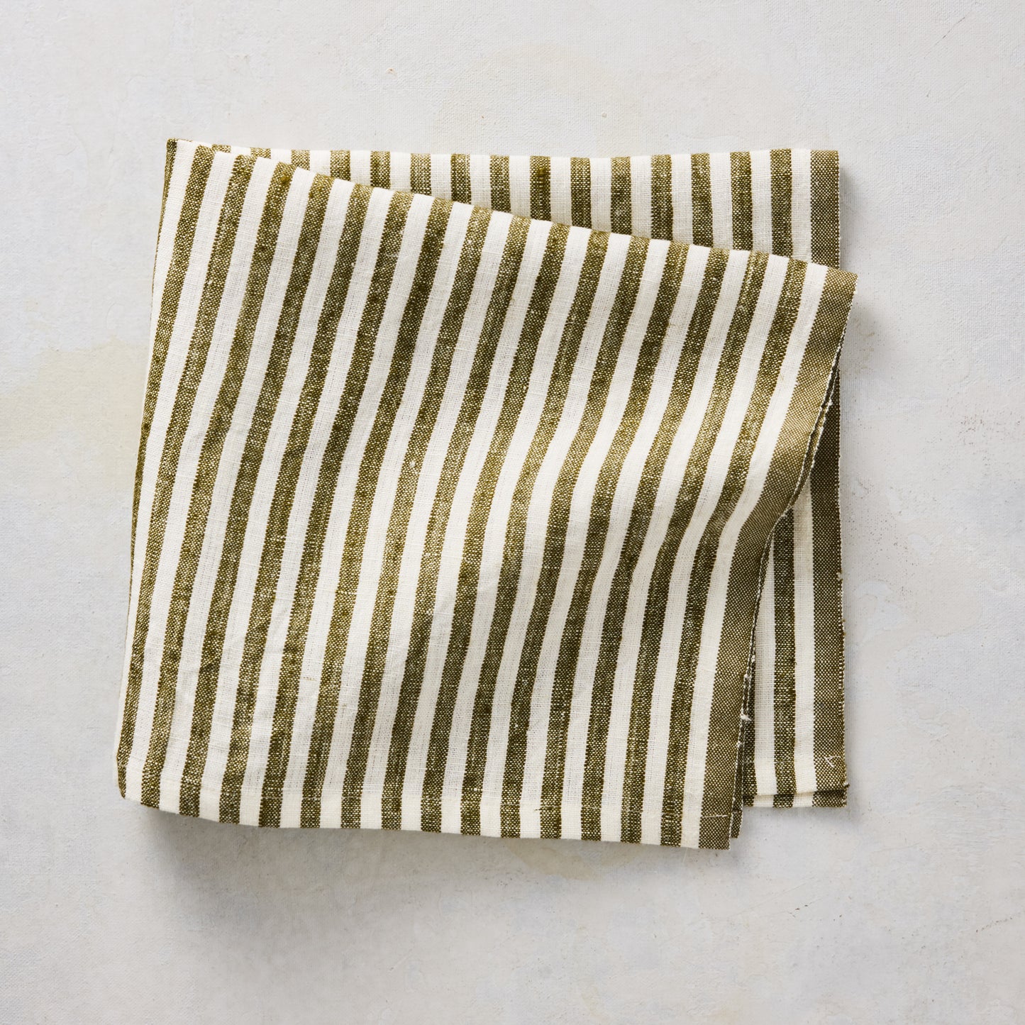 Folded 21-inch square linen napkin with green and white ticking stripes on a neutral background.