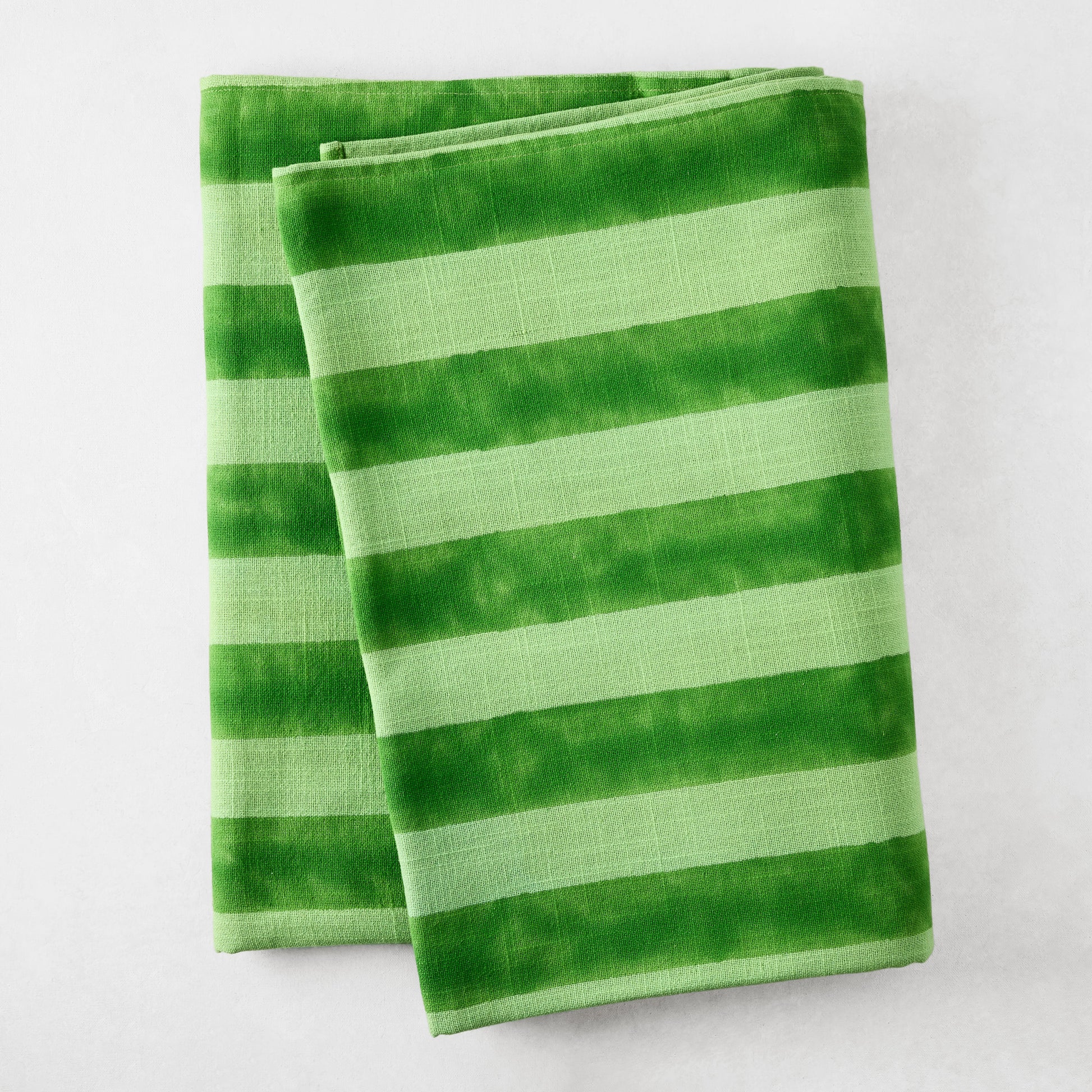 Folded Green Tonal Hampton Stripe Cotton Tablecloth with bold, two-toned green stripes.