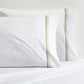Set of 2 white percale pillowcases with green triple stitch edging.