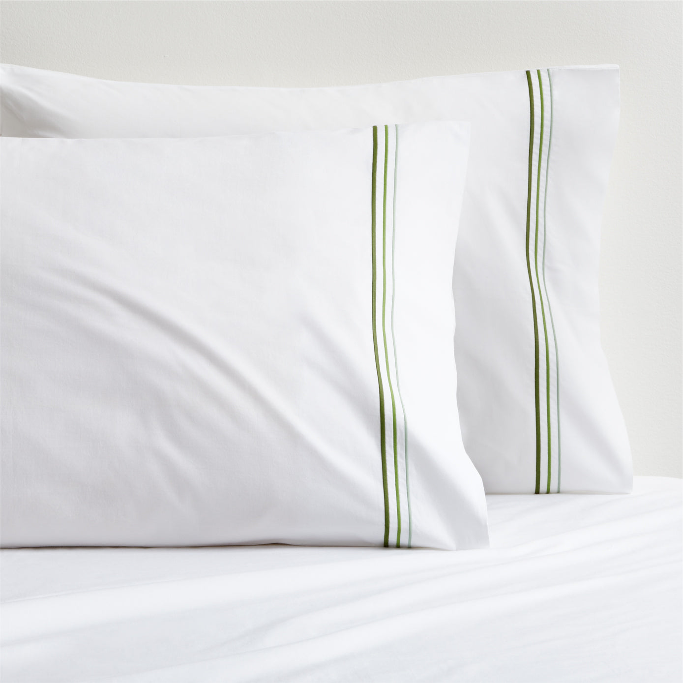 Set of 2 white percale pillowcases with green triple stitch edging.