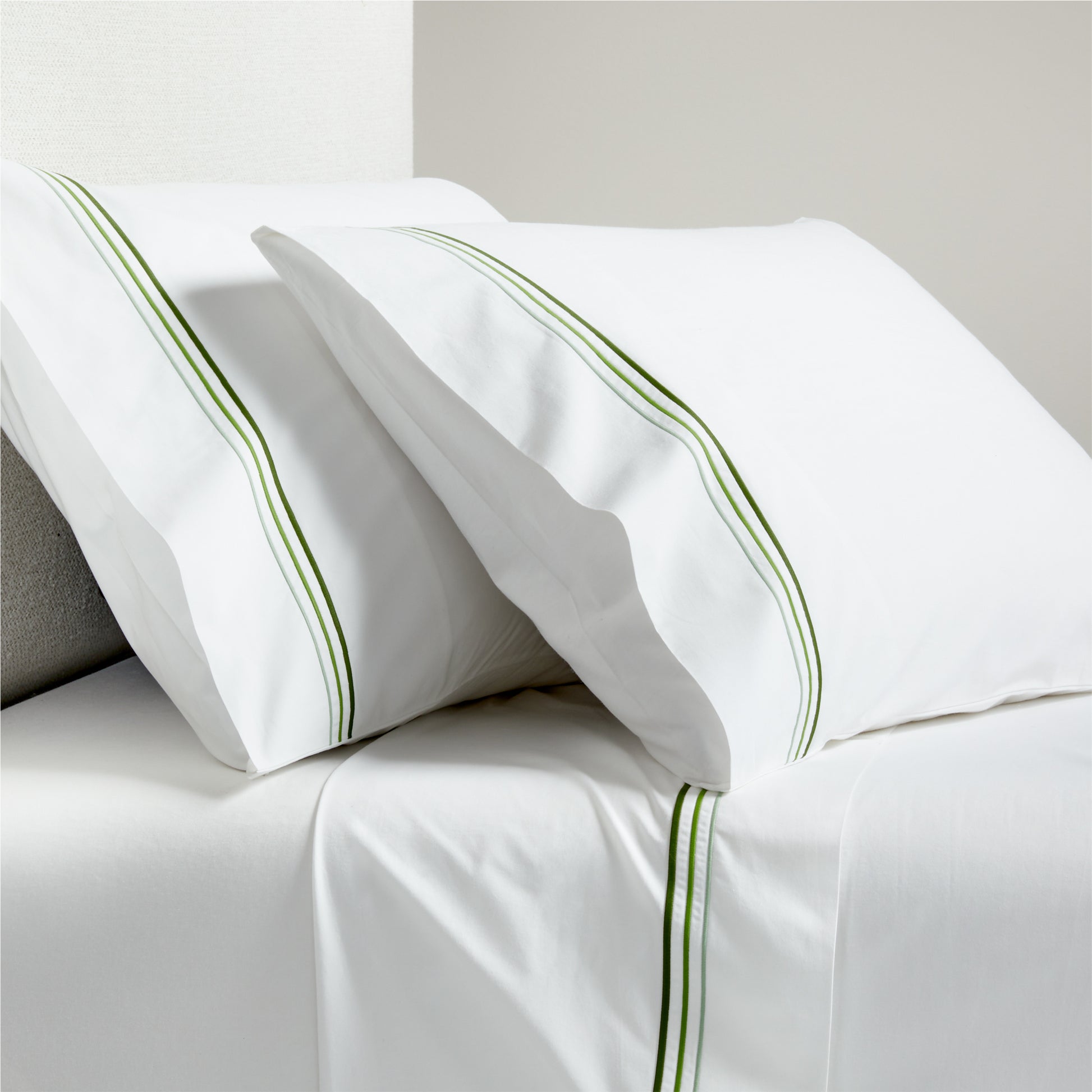 White percale sheet set with green triple-stitch trim on pillowcases and flat sheet.