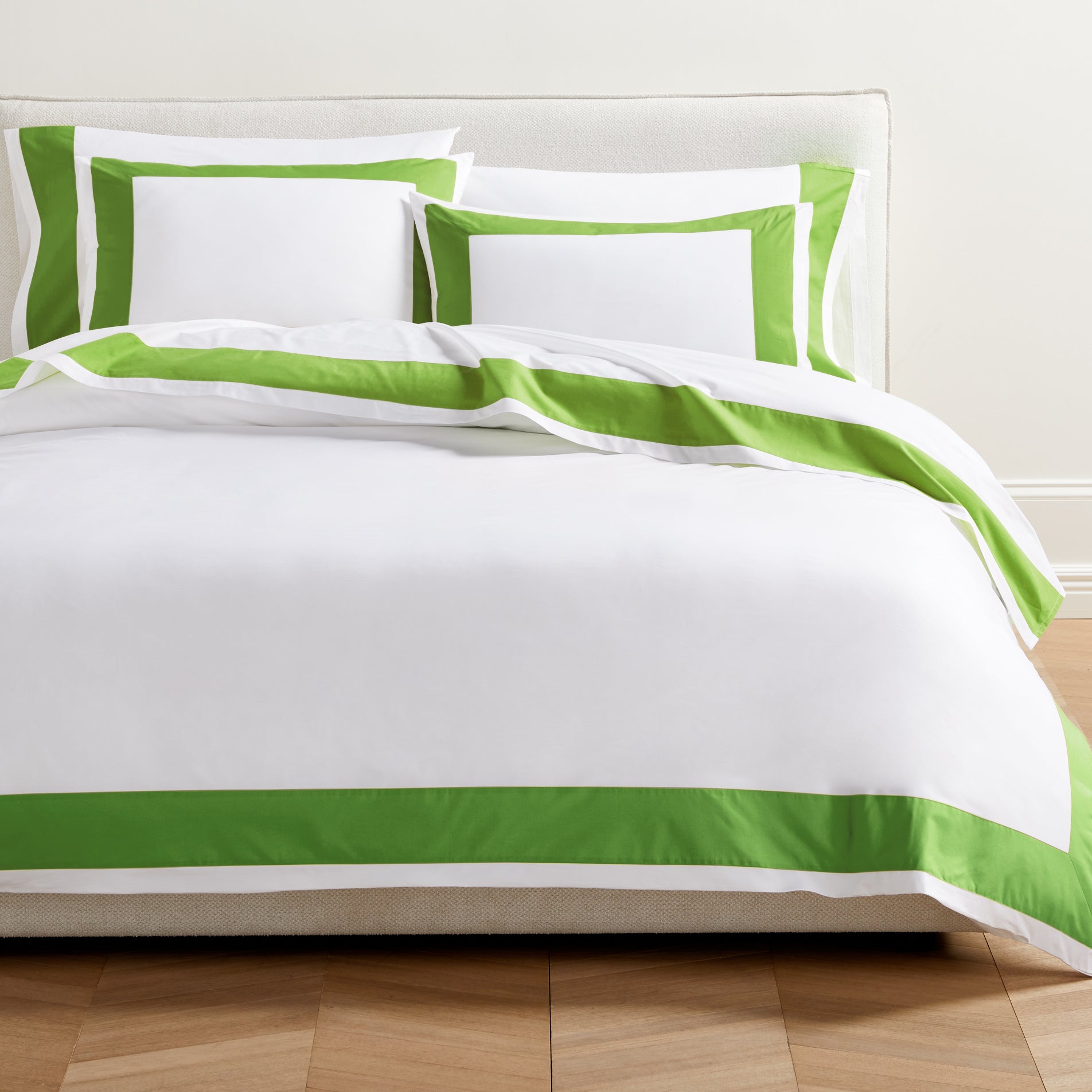 White percale duvet cover with a bold green wide-band border and matching shams on a bed.