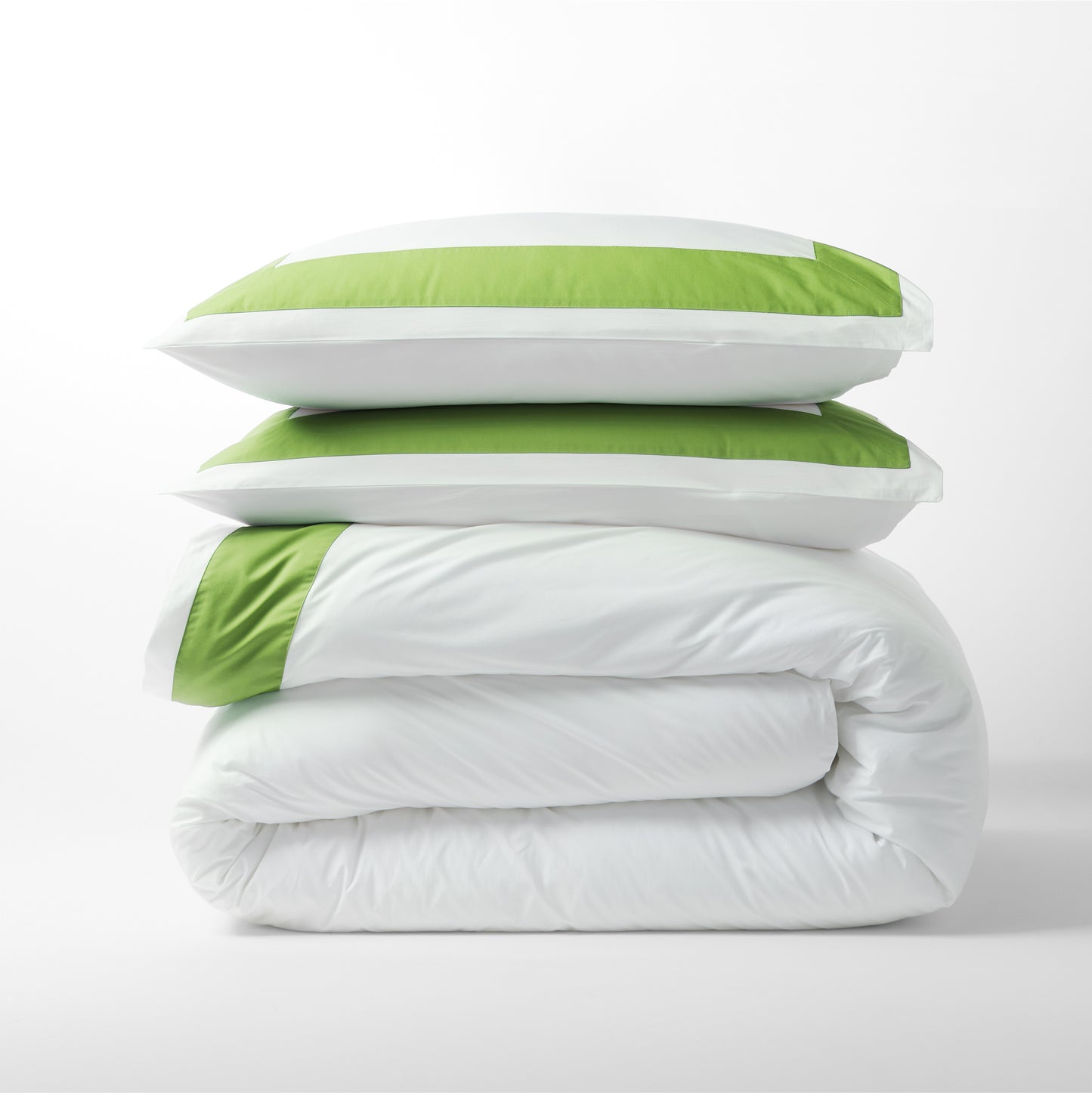 Stack of two white percale pillow shams with green wide bands and a folded white duvet.