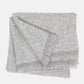 Folded Grey Azolla Alpaca Wool Throw Blanket with fringed edges and a subtle woven texture.