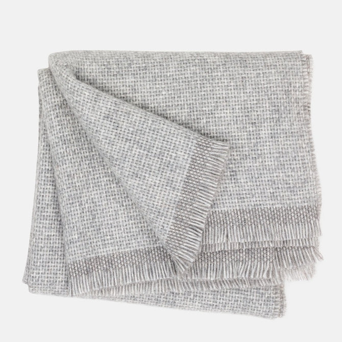 Folded Grey Azolla Alpaca Wool Throw Blanket with fringed edges and a subtle woven texture.