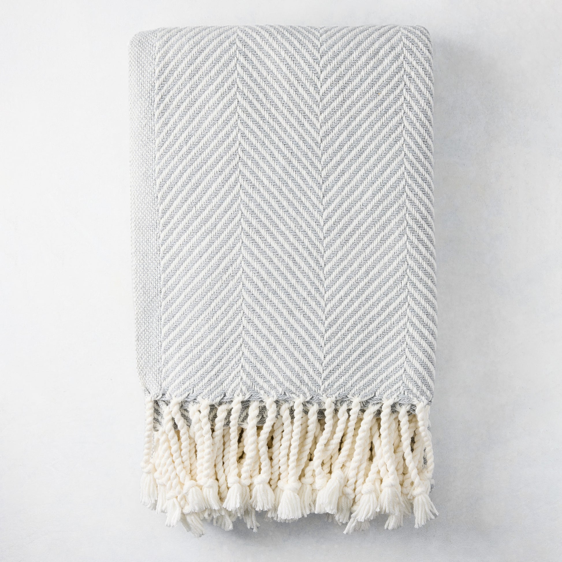 Grey chevron cotton throw blanket with thick rope fringe.
