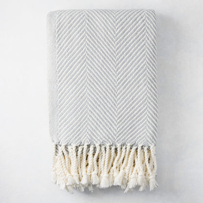 Grey chevron cotton throw blanket with thick rope fringe.