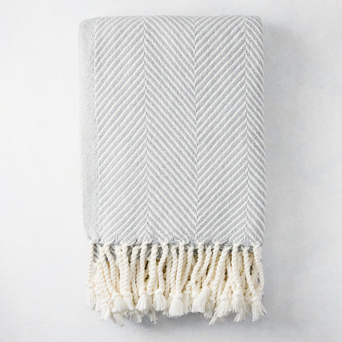 Grey chevron cotton throw blanket with thick rope fringe.