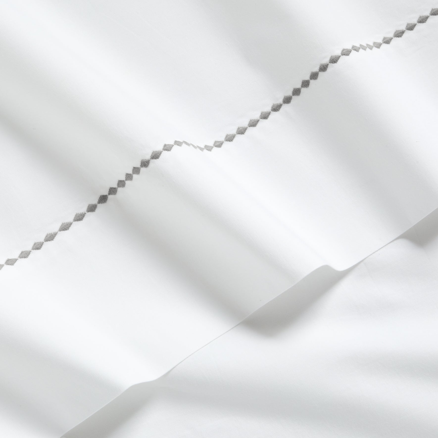 White percale sheet set with a grey diamond embroidered border.