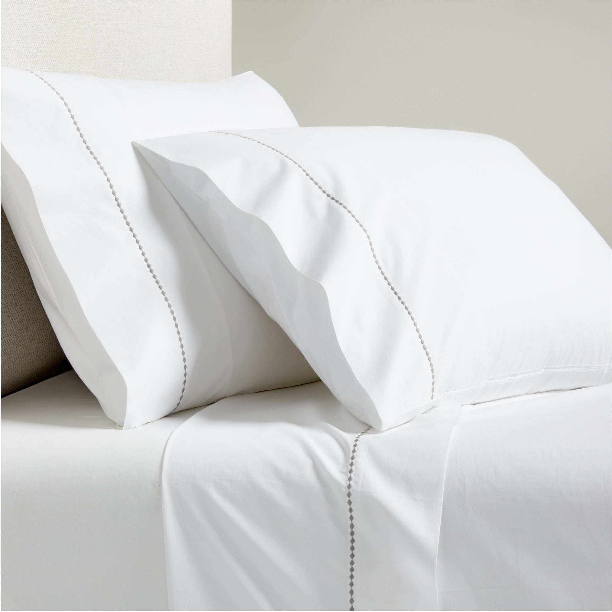 White percale sheet set with grey diamond embroidered trim on pillows and flat sheet.