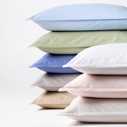 Stack of soft Italian percale pillow shams in various pastel colors: blue, green, white, lavender, pink, and beige.