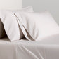 Grey Italian Percale Sheet Set with two pillowcases and flat sheet on a bed.